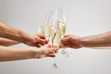 cropped view of men and women toasting while holding champagne glasses with sparkling wine isolated...