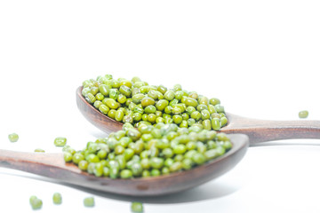 Wooden spoons of mung beans on a white background