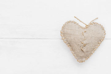 Darned heart on a wooden white background. Top view