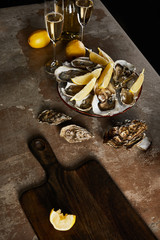 champagne glasses with sparkling wine near bottle, oysters and lemons in bowl