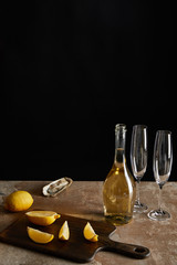 tasty oyster near lemons and bottle with sparkling wine isolated on black