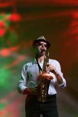 Obraz na płótnie Canvas Man and saxophone in laserlights on stage