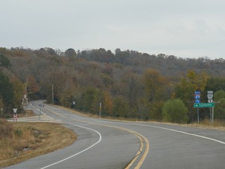Curbing roads with directional signs and distances to Fayetteville, Arkansas in autumn.