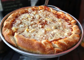 Close up of a giant pizza with thick crust and cheesy topping