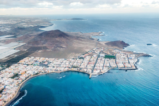 Airplane aerial view of coastal landscape and town of Arinaga on Gran Canaria island with ocean, hills and cities