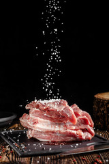 Raw pork meat lies on a cutting board, on a wooden table, next to a kitchen knife. Pickled meat in...