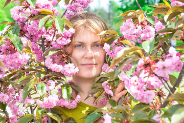 Young woman face with red hair in pink sakura flowers