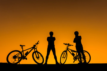 Family cyclist and Bicycle silhouettes on the dark background of sunsets