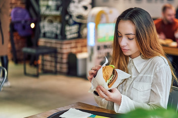 young woman in a cafe eating a burger
