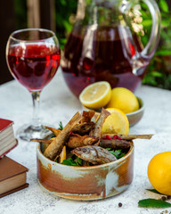 fried sprats with lemon and herbs and a glass of juice