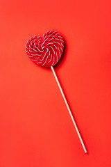 Heart shaped large red and white striped sugar lollipop. The concept of Valentine's Day, love and friendship. Minimal simple flat lay composition layout. Natural material and light