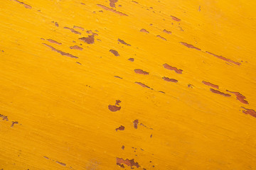 Texture of peeling yellow paint on an old wooden surface.