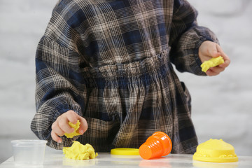 Toddler girl playing with modelling clay. Play dough allows kids to develop fine motor skills,...