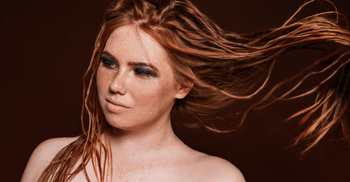 Woman with flying red dreadlocks hairstyle posing in studio. Blue glittered make-up. Smokey eyes