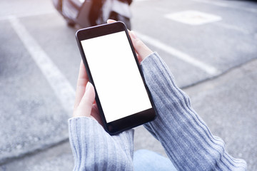  Mockup picture of business woman’s hands holding smart phone with white blank screen in modern place.