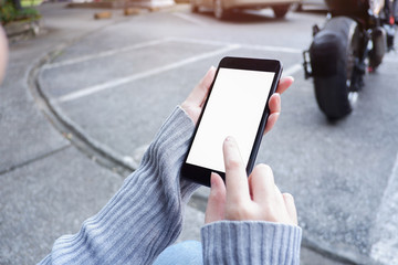  Mockup picture of business woman’s hands holding smart phone with white blank screen in modern place.