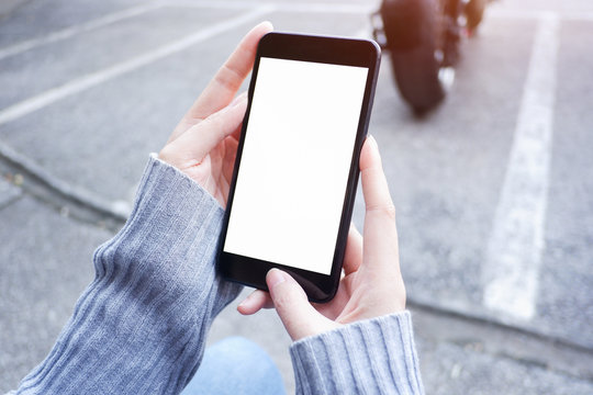  Mockup picture of business woman’s hands holding smart phone with white blank screen in modern place.
