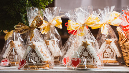 Christmas handmade gingerbread cookies on wooden shelf, small house shaped cake, packed with red and gold bow