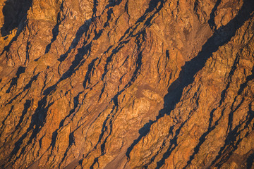 Sunny nature background of rockies in sunlight. Vivid natural mountain texture of big rough rocks. Full frame of bright giant craggy surface. Rocky mountain close-up. Plane of shiny rocks on sunset.