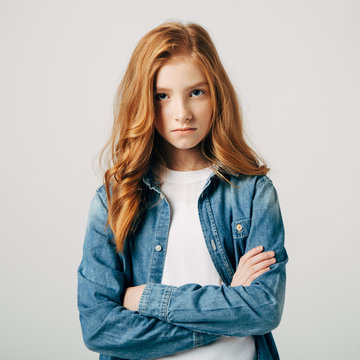 The red-haired teen girl is very offended by her parents. The blue-eyed cutie is upset. She is angry and look at the camera. Teen mood swings.