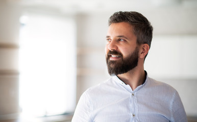 Front view portrait of mature man with white shirt standing indoors at home.