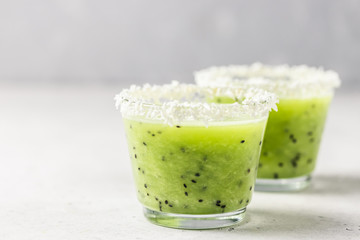Kiwi coconut flakes smoothie in glasses on light background. Selective focus, space for text.
