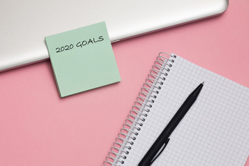 2020 goals text on notepad with pen on pink background. Business motivation, inspiration concept.