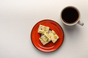 Nougat on a plate and a cup of tea on light background