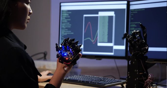Asian teenage engineer assembling and testing robotics arm responses in laboratory. Student engineer programming controller circuit synchronize technology and collaborating development robot.