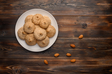 Almond biscuits on a plate on a wooden table. Top view