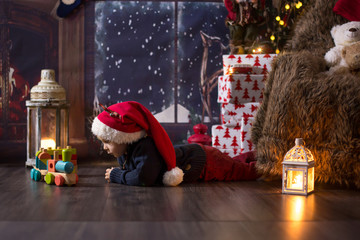 Sweet toddler boy, playing with wooden train at home at night on Christmas