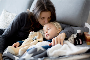 Blond toddler boy, sleeping on the couch in living room, lying down with fever