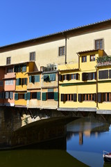 Fototapeta na wymiar Ponte Vecchio and Arno River with blue sky. Colorful windows close-up. Florence, Italy.
