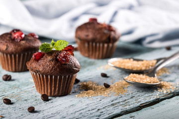 Chocolate fresh delicious muffins with cranberry on blue wooden background