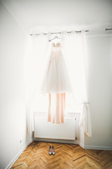 The perfect wedding dress with a full skirt on a hanger in the room of the bride