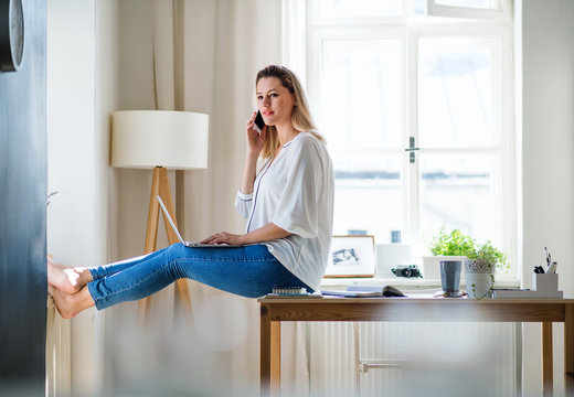 Young Woman With Smartphone And Laptop Indoors In Home Office, Working.