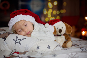 Fototapeta na wymiar Sweet beautiful blond toddler boy, sleeping in bed with toy