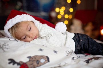 Sweet beautiful blond toddler boy, sleeping in bed with toy