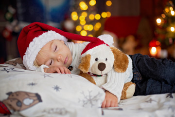 Sweet beautiful blond toddler boy, sleeping in bed with toy