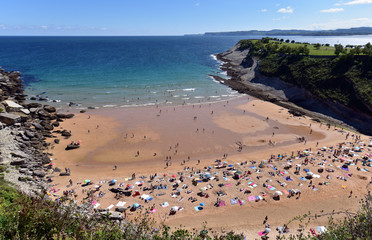 Fototapeta na wymiar Tourists enjoying hot August weather on Beach Playa de Matalenas in Santander, Cantabria, Northern Spain