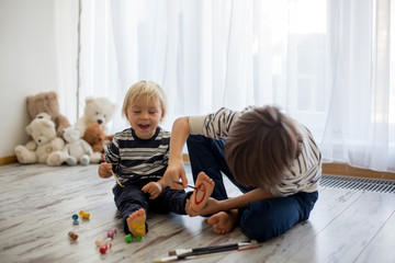 Brothers, playing at home, painting on their feet, tickling, laughing, smiling