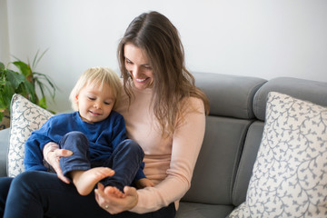 Mother, tickling her little toddler boy, child giggling at home