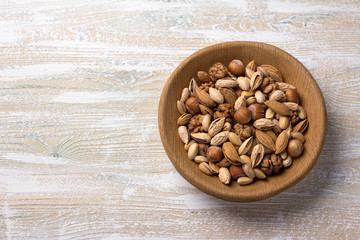 Variety of nuts in wooden bowl over wooden table. almonds, walnuts, hazelnuts, pistachios. rustic style. horizontal	