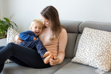 Mother, tickling her little toddler boy, child giggling at home