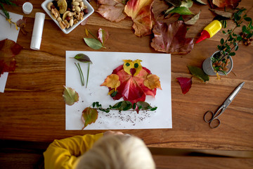 Sweet child, toddler boy, applying leaves using glue