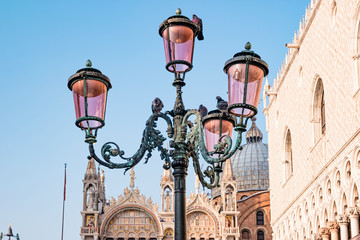 Fototapeta na wymiar Famous venezian street lamps with pink glass in front of Basilica di San Marco in Venice, Italy