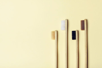 Four eco-friendly bamboo toothbrushes on a yellow background. Zero waste concept, plastic-free, organic, eco-friendly shopping