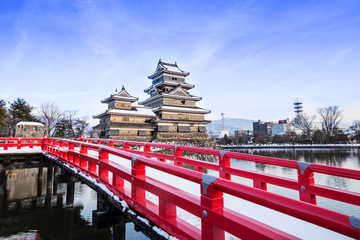 old castle in japan. Matsumoto castle against blue sky in Nagono city, Japan.Castle in Winter with heavy snowfall.Travel Matsumoto Castle with frozen pond in Winter.a Japanese premier historic castles