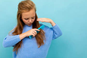 cute european girl combing her hair on a light blue background