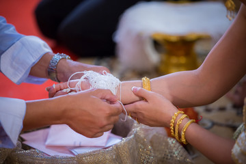 bind holy thread with hand in thai rite.The bride's hands are tied with thread from the older culture in Thailand.